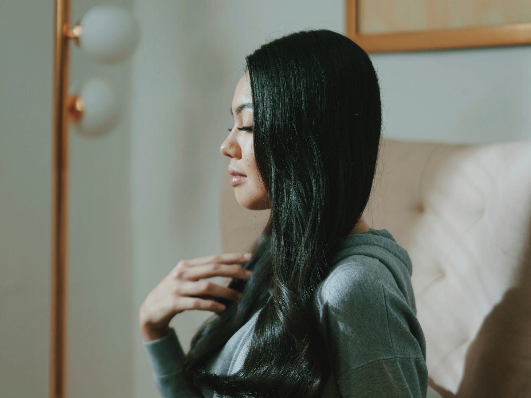 A woman sitting in an armchair with her eyes closed and one hand resting on her chest